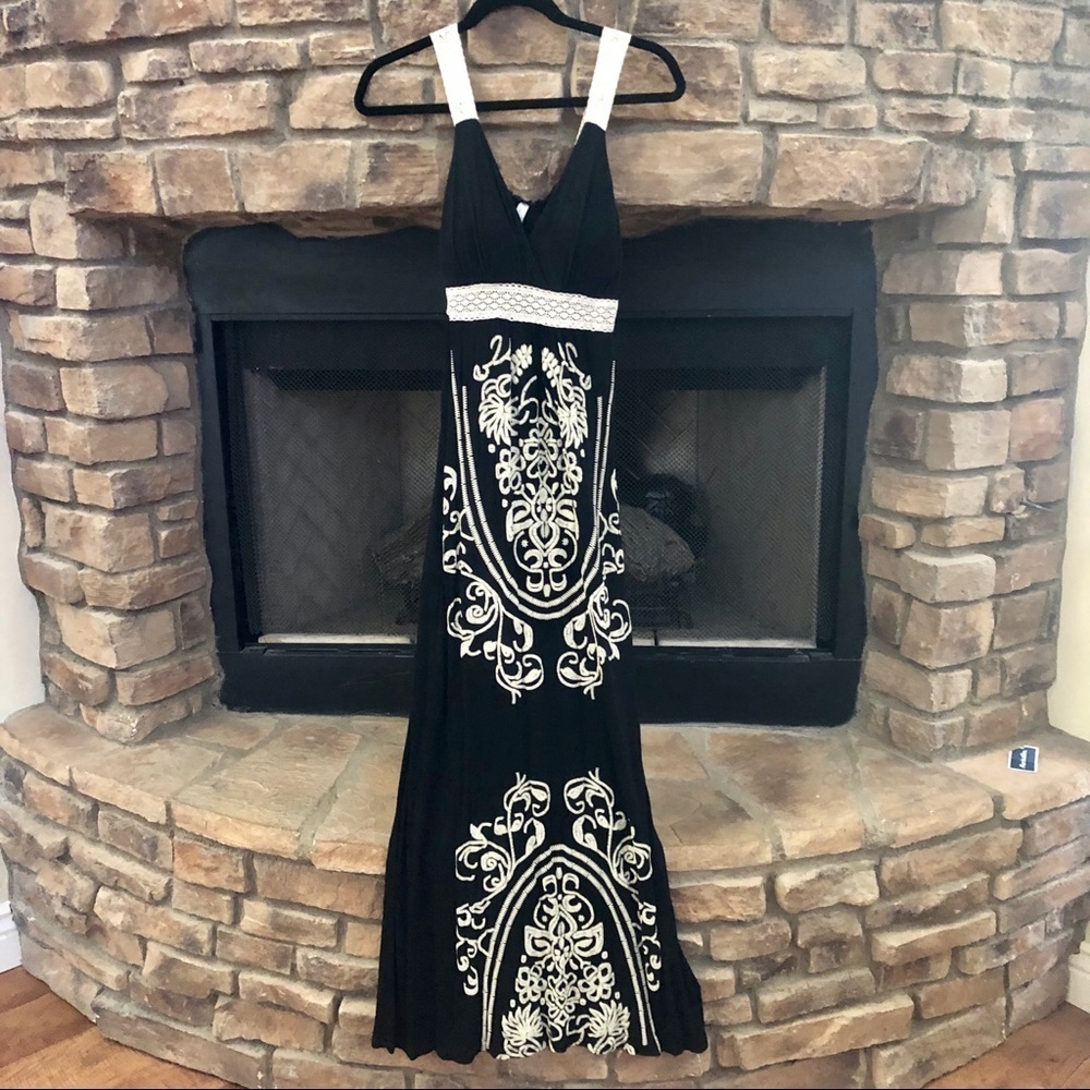 Long black dress with intricate embroidery throughout and white lace straps. Med